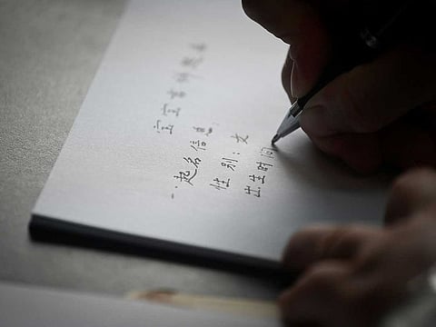Yang Yiren, Chinese naming expert at the Three-Arts Yijing Research Centre Beijing, giving a name to a man's newborn daughter at his office in Beijing.