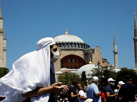 A man gestures as people wait for the beginning of Friday prayers outside Hagia Sophia Grand Mosque, for the first time after it was once again declared a mosque after 86 years, in Istanbul, Turkey, July 24, 2020. 