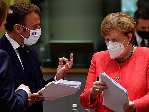 German Chancellor Angela Merkel (right) discusses with French President Emmanuel Macron during a round table meeting at an EU summit in Brussels on July 20, 2020. 