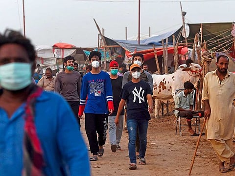In this picture taken on July 22, 2020, customers wearing facemasks arrive at a cattle market ahead of Eid Al Adha or the 'Festival of Sacrifice', in Pakistan's port city of Karachi.