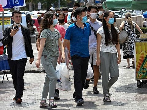 Youths in face masks walk through a street market in Bishkek, Kyrgyzstan, Friday, July 24, 2020.