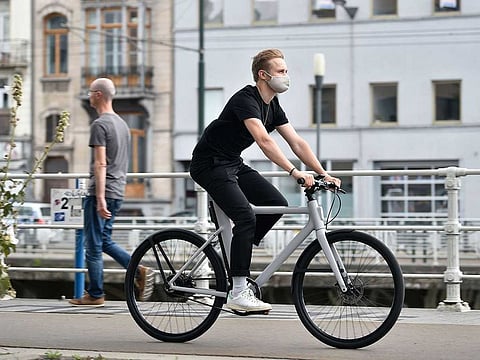 A Cowboy employee, wearing a protective face mask, rides one of the brand's electric bikes in Brussels.
