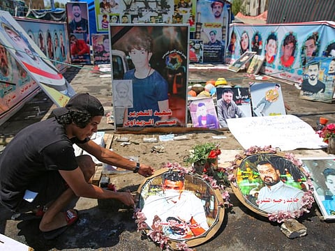An Iraqi anti-government demonstrator arranges portraits of killed protesters in Tahrir Square in the capital Baghdad, on August 1, 2020. 