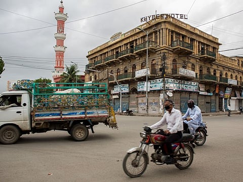 A motorcyclist wearing a protective mask ride through a near-empty junction in Karachi, Pakistan. The mega-city is the capital of Sindh province.