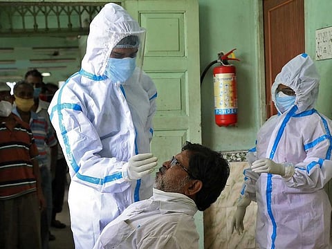 A healthcare worker wearing personal protective equipment (PPE) takes a swab from a man for a rapid antigen test as others wait for their turn at a check-up centre, amidst the spread of the coronavirus disease (COVID-19), in Kolkata, India, July 31, 2020. 