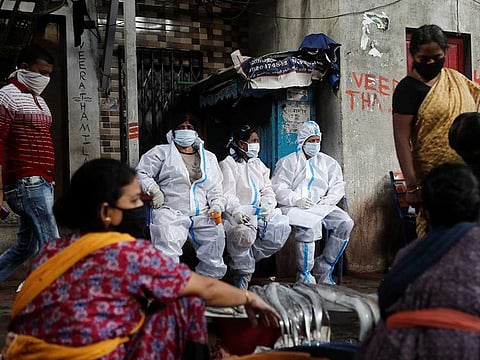 Health workers in personal protective equipment rest during a check up campaign for the coronavirus disease (COVID-19) at a slum area in Mumbai, India, August 3, 2020.