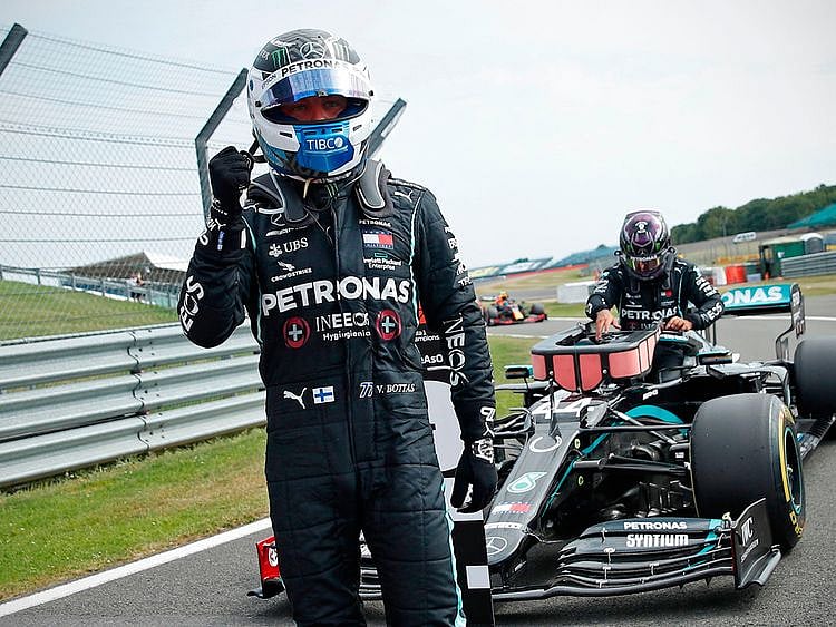 Mercedes' Finnish driver Valtteri Bottas celebrates in the pit lane as Mercedes' British driver Lewis Hamilton (back) gets out of his car after the qualifying session of the F1 70th Anniversary Grand Prix at Silverstone on August 8, 2020 in Northampton. - This weekend's race will commemorate the 70th anniversary of the inaugural world championship race, held at Silverstone in 1950. (Photo by ANDREW BOYERS / POOL / AFP)