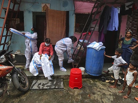 Health workers put on a protective suit before screening people for COVID-19 symptoms in Dharavi , one of Asia's biggest slums, in Mumbai on August 11, 2020. 