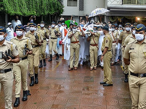 Police personnel escort the draped coffin (C) of Indian classical vocalist Pandit Jasraj during his funeral in Mumbai on August 20, 2020.