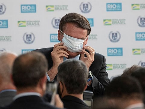 Brazil's President Jair Bolsonaro puts on a mask.
