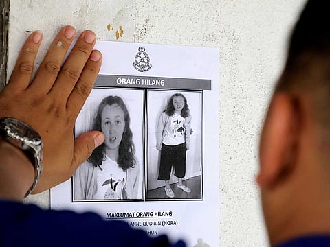 A police officer pastes a photo of 15-year-old Irish girl Nora Anne Quoirin who went missing from a resort on a wall at a shop in Seremban, Malaysia, August 9, 2019.
