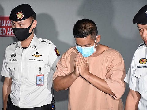 Prasitthichai Khaewkao, centre, arrives at the Bangkok Criminal Court in Bangkok, Thailand, Thursday, Aug, 27, 2020. The court handed a death sentence Thursday to an elementary school principal who fatally shot dead three people including a toddler when he robbed a gold shop earlier this year. 