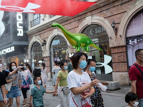 People wearing protective masks walk past an Under Armour Inc. store in a shopping area in Wuhan. 