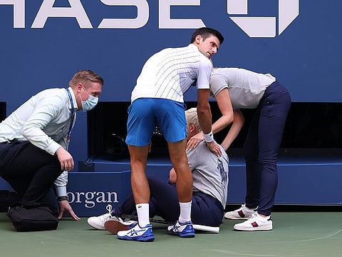 Novak Djokovic tends to a line judge after hitting her with a ball.