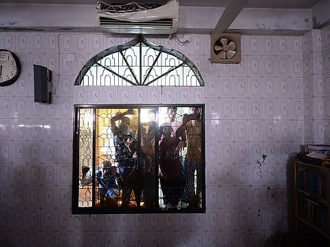 Onlookers peep through a broken window of a mosque following a fire in the central district of Narayanganj, on September 5, 2020.