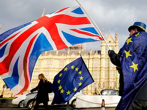 In this file photo taken on March 28, 2018 An anti-Brexit demonstrator waves a Union flag alongside a European Union flag outside the Houses of Parliament in London. The British government said on September 7, 2020, that it was taking steps to "clarify" how Northern Ireland's trade will be handled after Brexit, but insisted it remained committed to its EU withdrawal agreement and the province's peace process. 