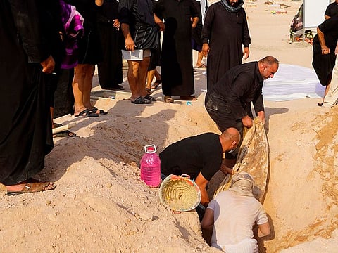An Iraqi family digs up the corpse of a relative, who died of the novel coronavirus, at a coronavirus cemetery in a plot of desert outside the Shiite holy city of Najaf to be transferred to a family cemetery for reburial 