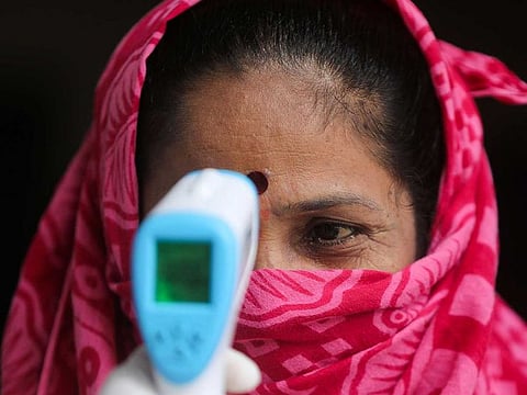 Community health volunteers check the temperature of a woman at a slum area during a check up campaign for the coronavirus disease (COVID-19) in Mumbai, India, September 16, 2020. 