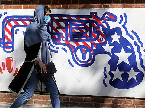 A woman, wearing a protective mask amid the COVID-19 pandemic, walks past a mural painted on the outer walls of the former US embassy in the Iranian capital Tehran on September 20, 2020. Iran called on the rest of the world to unite against the United States, after Washington unilaterally declared UN sanctions against the Islamic republic were back in force. 