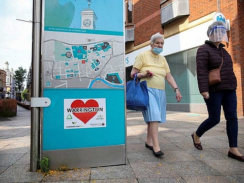 Women wearing a protective mask and a face shield walk past a city map, amid the coronavirus disease (COVID-19) outbreak, in Warrington, Britain September 22, 2020.