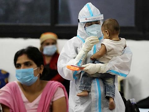 A medical worker in personal protective equipment (PPE) plays with a child of a woman recovering inside a quarantine centre for the coronavirus disease (COVID-19) patients amidst the spread of the disease at an indoor sports complex in New Delhi