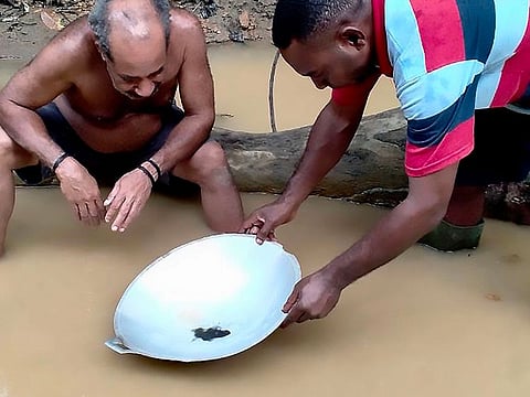 This picture taken on July 7, 2020 shows two miners panning for gold along a stream near Korowai, Papua province.