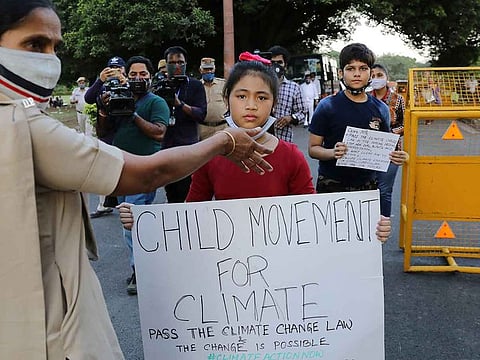 Licypriya Kangujam, 8, India's young climate activist, carrying a placard is stopped by a policewoman during a protest demanding to pass a climate change law outside the parliament in New Delhi, India, September 23, 2020. 