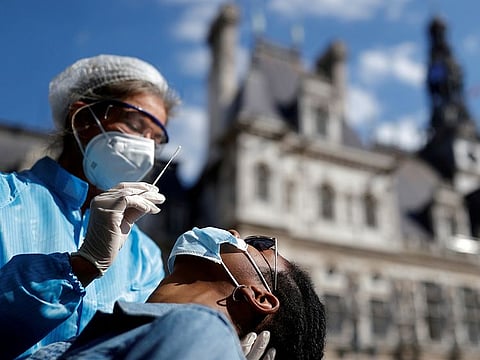 A health worker, wearing a protective suit and a face mask, prepares to administer a nasal swab to a patient at a testing site for the coronavirus disease (COVID-19) installed in front of the city hall in Paris, France, September 2, 2020. 