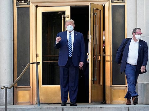 US President Donald Trump wears a protective mask while walking out of Walter Reed National Military Medical Center to board Marine One 