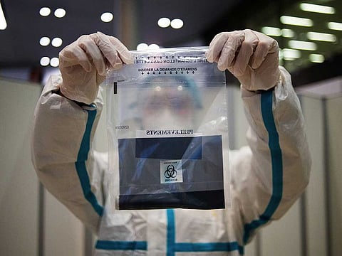 A health worker holds a bag containing a completed COVID-19 swab test at Charles de Gaulle airport, operated by Airport de Paris, in Roissy, France, on Tuesday, Oct. 6, 2020.
