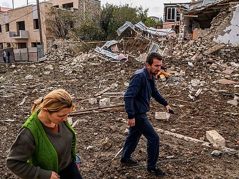 A couple walk in front of a destroyed house after a late October 7th shelling in the breakaway Nagorno-Karabakh region's main city of Stepanakert on October 8, 2020, during the ongoing fighting between Armenia and Azerbaijan over the disputed region. 