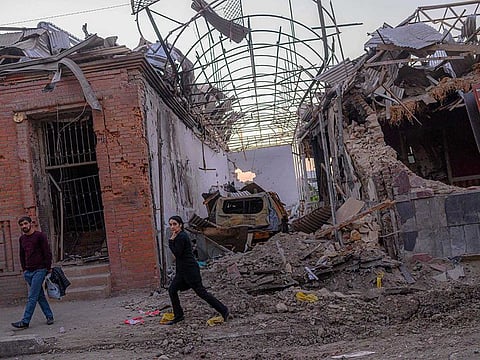 Local residents walk in a street after it was hit by a missile in Gandja, Azerbaijan, on October 8, 2020, near the disputed Nagorno-Karabakh province's capital Stepanakert as fighting between Armenian and Azerbaijani forces spilled over ahead of a first meeting of international mediators in Geneva. 