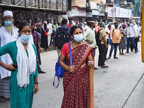 Commuters wait to board a bus as train services shut down after a grid failure that resulted in massive power outages across the city, in Mumbai, Monday, Oct. 12, 2020.