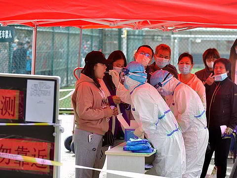 A medical staff takes a swab from a woman as residents line up for the COVID-19 test near the residential area in Qingdao in east China's Shandong province, Monday, Oct. 12, 2020.