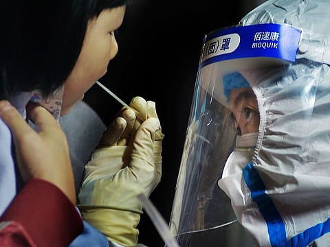 A medical staff takes a swab from a child near a residential area in Qingdao in east China's Shandong province on Tuesday, Oct. 13, 2020