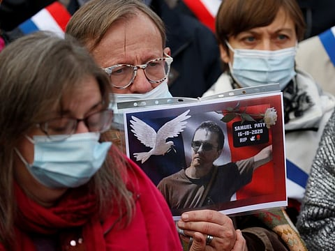 A person holds a picture of Samuel Paty, the French teacher who was beheaded on the streets of the Paris suburb of Conflans St Honorine, during a tribute at the Place de la Republique, in Lille, France, October 18, 2020. 