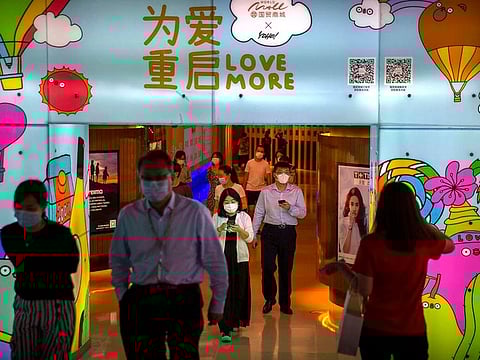 File picture: People wearing face masks to protect against the coronavirus walk through a shopping mall in Beijing in August 2020..