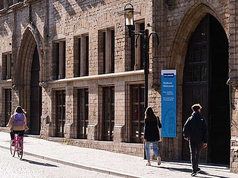A cyclist and pedestrians pass an entrance to Leuven University in Lueven, Belgium, on Monday, Oct. 19, 2020. Belgium announced new measures to control the rapid spread of coronavirus, which will see cafes, bars and restaurants closed nationwide for four weeks, and working from home will becoming mandatory where possible.