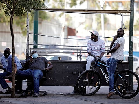 Sudanese migrants sit as they wait for work on a street corner in south Tel Aviv, Israel October, 25, 2020. 