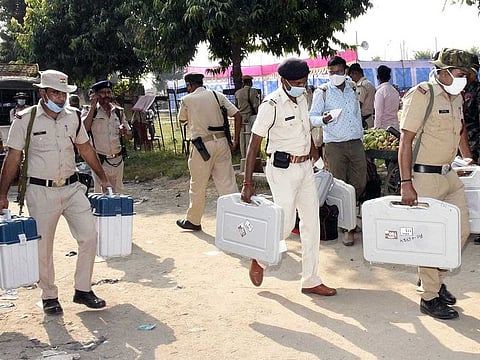 Security personnel carrying Electronic Voting Machines (EVMs) on the eve of the first phase of Bihar Assembly Elections, at Paliganj in Patna district on Tuesday. 