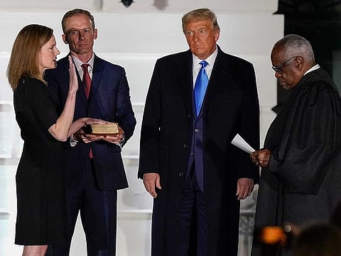 President Donald Trump watches as Supreme Court Justice Clarence Thomas administers the Constitutional Oath to Amy Coney Barrett on the South Lawn of the White House White House in Washington, Monday, Oct. 26, 2020, after Barrett was confirmed to be a Supreme Court justice by the Senate earlier in the evening. Holding the Bible is Barrett's husband, Jesse Barrett. 