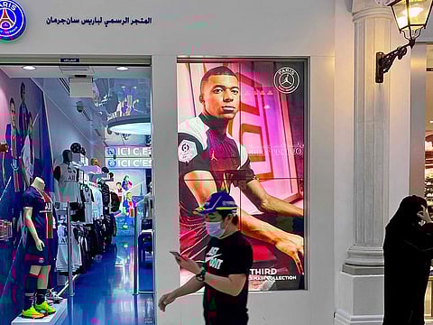 A masked shopper in front of a Paris St-Germain store