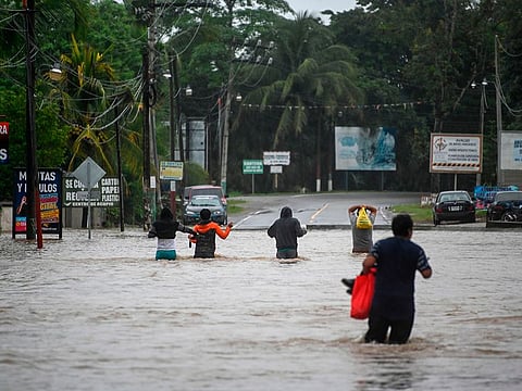 Residents walk in a flooded area due to the heavy rains caused by Hurricane Eta, now degraded to a tropical storm, at Las Posas village in Morales, Izabal, 220 km north Guatemala City on November 5, 2020. 
