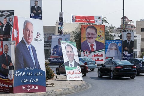 Cars advance on a road lined with campaign banners and slogans of candidates for the upcoming Jordanian parliamentary elections in the capital Amman, on November 3, 2020.
