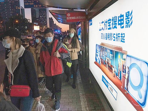 Residents wearing masks to protect from the coronavirus pass by an ad promoting 50% for online movies during the November 11 Sales Day, in Beijing.
