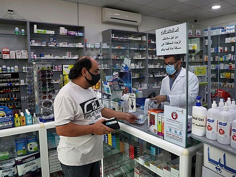 Pharmacist Ziad Jomaa sells medicine to a customer in his pharmacy in Bchamoun village outside of Beirut, Lebanon, Wednesday, Oct. 28, 2020. Drugs for everything from diabetes and blood pressure to anti-depressants and fever pills used to deal with COVID-19 have disappeared from shelves around Lebanon. Officials and pharmacists say the shortage was fueled by panic buying after the governor of the Central Bank suggested he will cut subsidies on medicines.