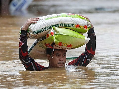File photo: A man carries sacks of rice over floodwaters as it continues to rise in the Philippines. An Orange warning alert — which foresees rivers overflowing and inundating some low-lying areas — is up in five provinces in Mindanao on Thursday (April 7, 2022).