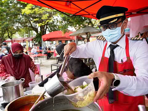 Former pilot Azrin Mohamad Zawawi prepares a curry laksa noodle dish at his food stall in Subang Jaya, Selangor, Malaysia, Wednesday, Nov. 4, 2020. Captain Azrin, a former Malindo airline pilot, lost his job after he was retrenched along with 2,200 other crew and staff late October due to the coronavirus outbreak. He now runs a small 'Kapten Corner' food stall selling local food while he waits for the aviation industry to recover. 