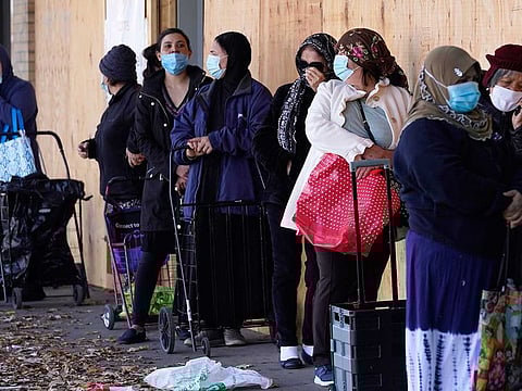 People wear face masks as they wait for an ICNA (Islamic Circle of North America) Relief Resource Centre and Food Pantry to open during the COVID-19 pandemic in Chicago, Thursday, Nov. 12, 2020. ICNA Relief provides social services across the US to the underprivileged and those affected by natural disasters.