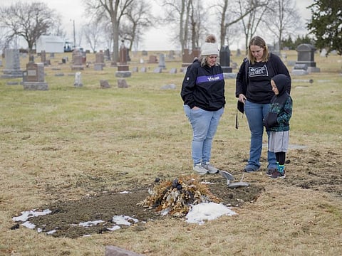 Relatives visit the grave of Doug Raysby, from left: Kathy James, mother-in-law; Katrina Raysby, wife; and Kalvin Jorgensen, stepson, in Geddes, South Dakota, Saturday, November 14, 2020. 